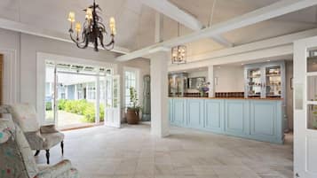 A spacious living area with a light blue kitchen, a chandelier, and a view of the outdoors.