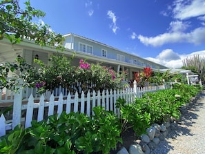 A two-story house with a white picket fence, surrounded by lush greenery and flowering plants. - Panamonte Hotel (Boquete)