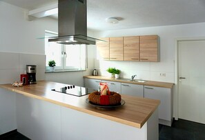 A modern kitchen with a wooden countertop, stainless steel appliances, and light wood cabinets. - Spacious vacation apartment with terrace & 3 bedrooms on the Swabian Alb (Blaubeuren)