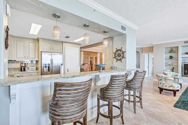 A modern kitchen with white cabinets, stainless steel appliances, and a central island with bar stools.