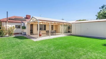 Enjoy an outdoor space with a covered patio, dining table, and chairs, surrounded by a well-maintained lawn.
