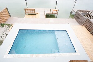 A rectangular pool with a tiled edge, surrounded by a wooden deck.