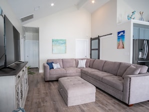 A modern living room with a sectional sofa, a flat-screen TV, and a wooden cabinet.
