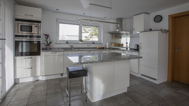 A modern kitchen with stainless steel appliances, a large island, and a window providing natural light. - Great detached house near Lake Constance (Lauterach)
