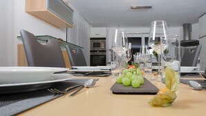 A dining area with a table set for four, including plates, cutlery, and a centerpiece of green grapes. - Great detached house near Lake Constance (Lauterach)