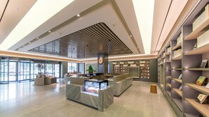 A spacious lobby with a reception desk, seating area, and a large bookshelf.