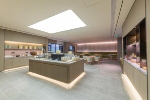 A modern hotel lobby with a central island, seating area, and a large window.