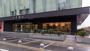 A modern hotel with a glass facade, a prominent entrance, and a well-lit interior.