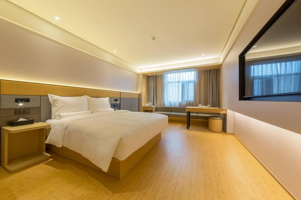 Una habitación de hotel moderna con una cama grande, mesitas de noche, un escritorio y un espejo.