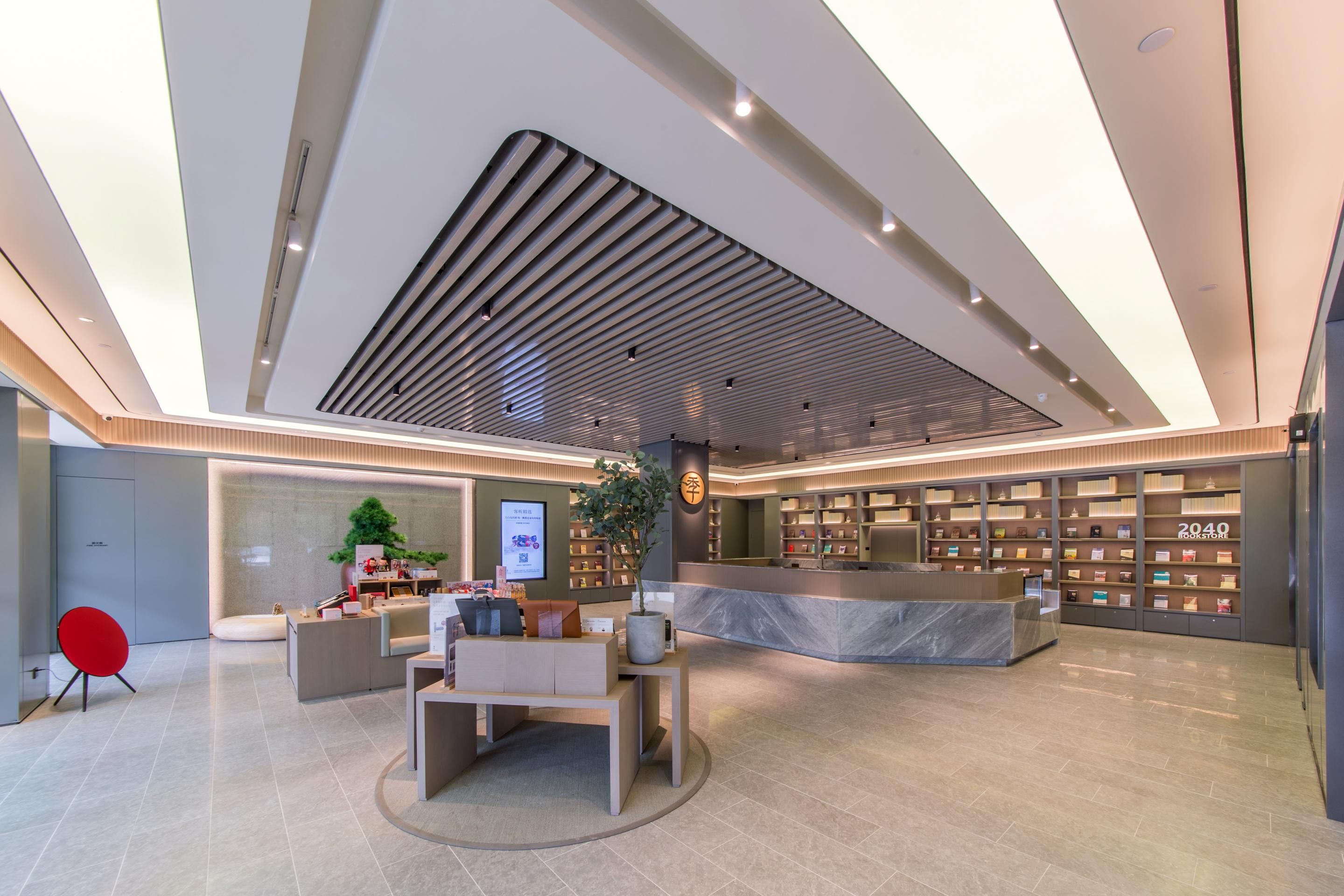 Un moderno vestíbulo de hotel con un mostrador de recepción, zona de estar y una exhibición de libros.