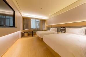A hotel room with two beds, a desk, a chair, a small table, a trash bin, and a window with curtains. - Ji Hotel (Wuhan)