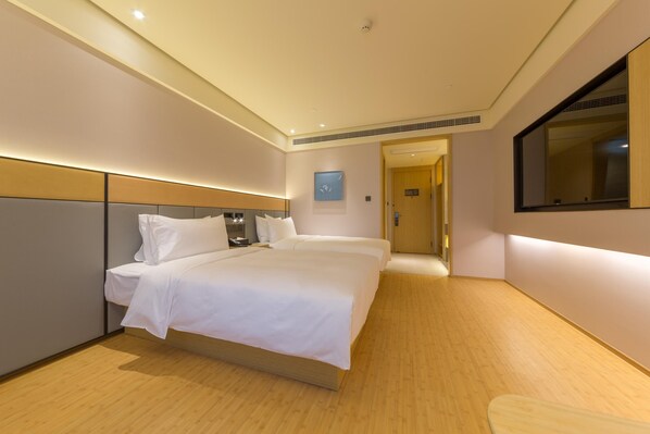 A hotel room with a large bed, a bedside table, a mirror, and a door leading to another room.