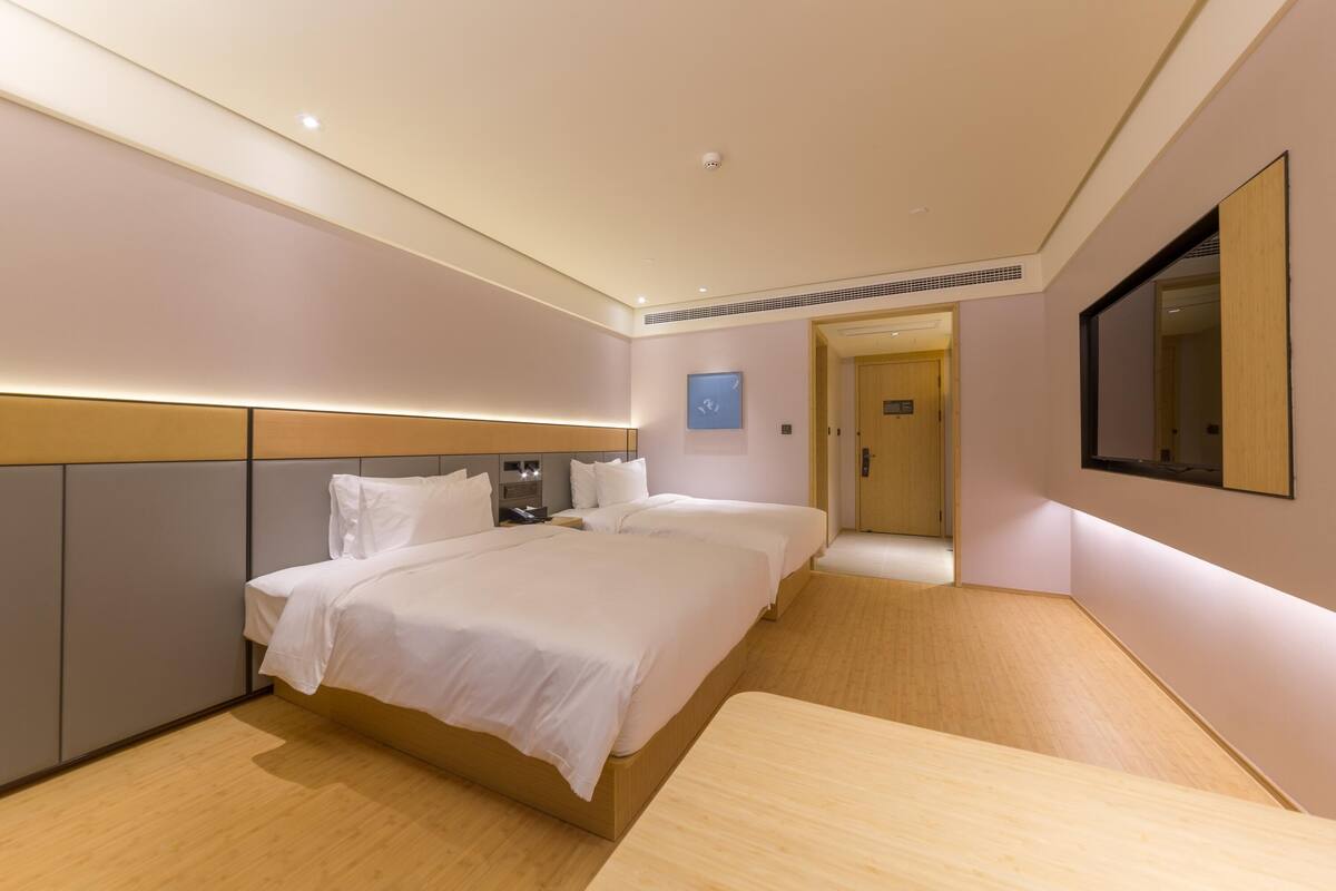 Habitación de hotel con una cama grande, mesitas de noche, un espejo y un reloj en la pared.