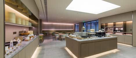 A modern hotel lobby with a central island, seating area, and a view of the city.