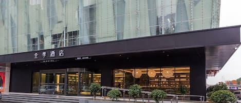 A modern hotel with a glass facade, a prominent entrance, and a well-lit interior.