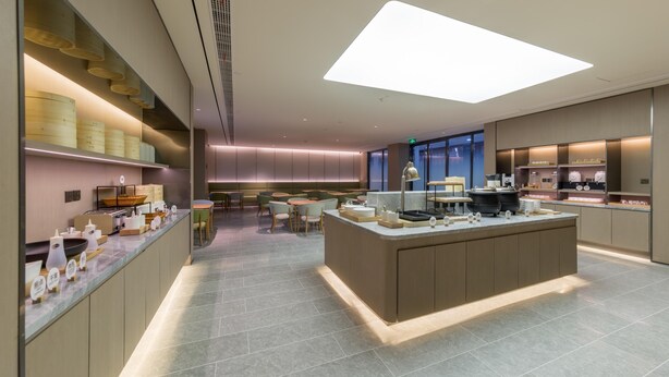 A modern hotel lobby with a central island, seating area, and a view of the city.
