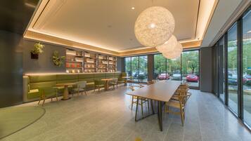 Un interior modern amb una taula de dinar llarga, seients i una biblioteca.