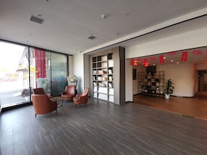 A modern interior with a seating area, a bookshelf, and a view through a glass wall. - Hanting Hotel (Beijing)