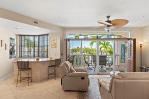 Relax in a spacious living area with a comfortable sofa, bar area, and sliding glass door leading to an outdoor patio with seating.