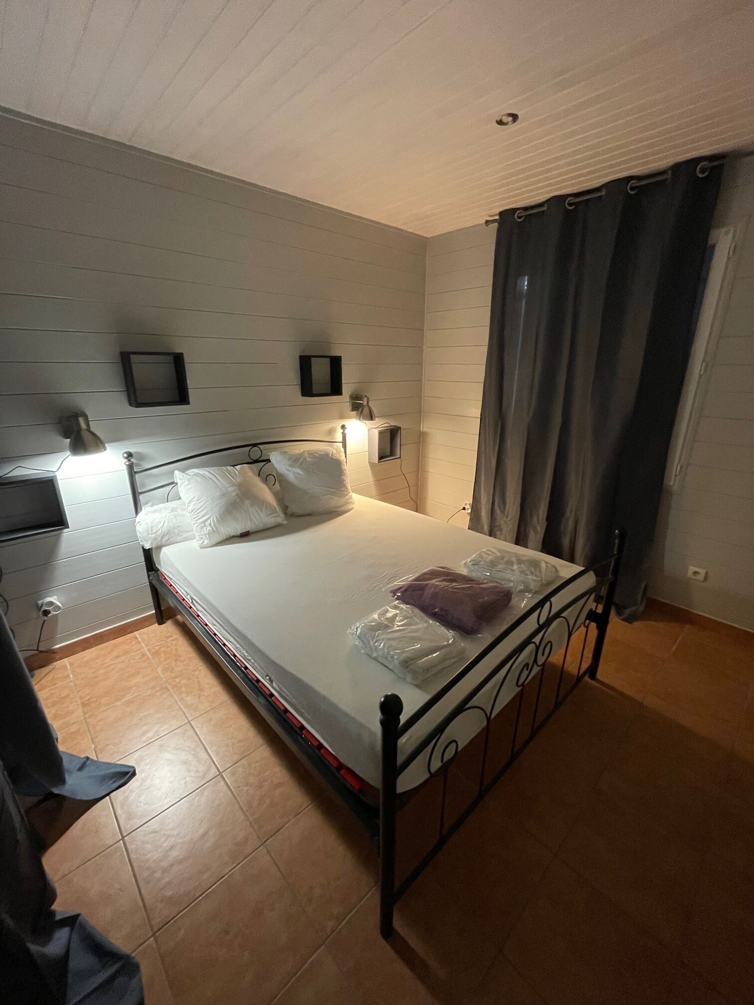 Camera da letto con un letto singolo, un comodino, una lampada e un punto luce a parete.
