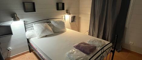 Camera da letto con un letto singolo, un comodino, una lampada e un punto luce a parete.