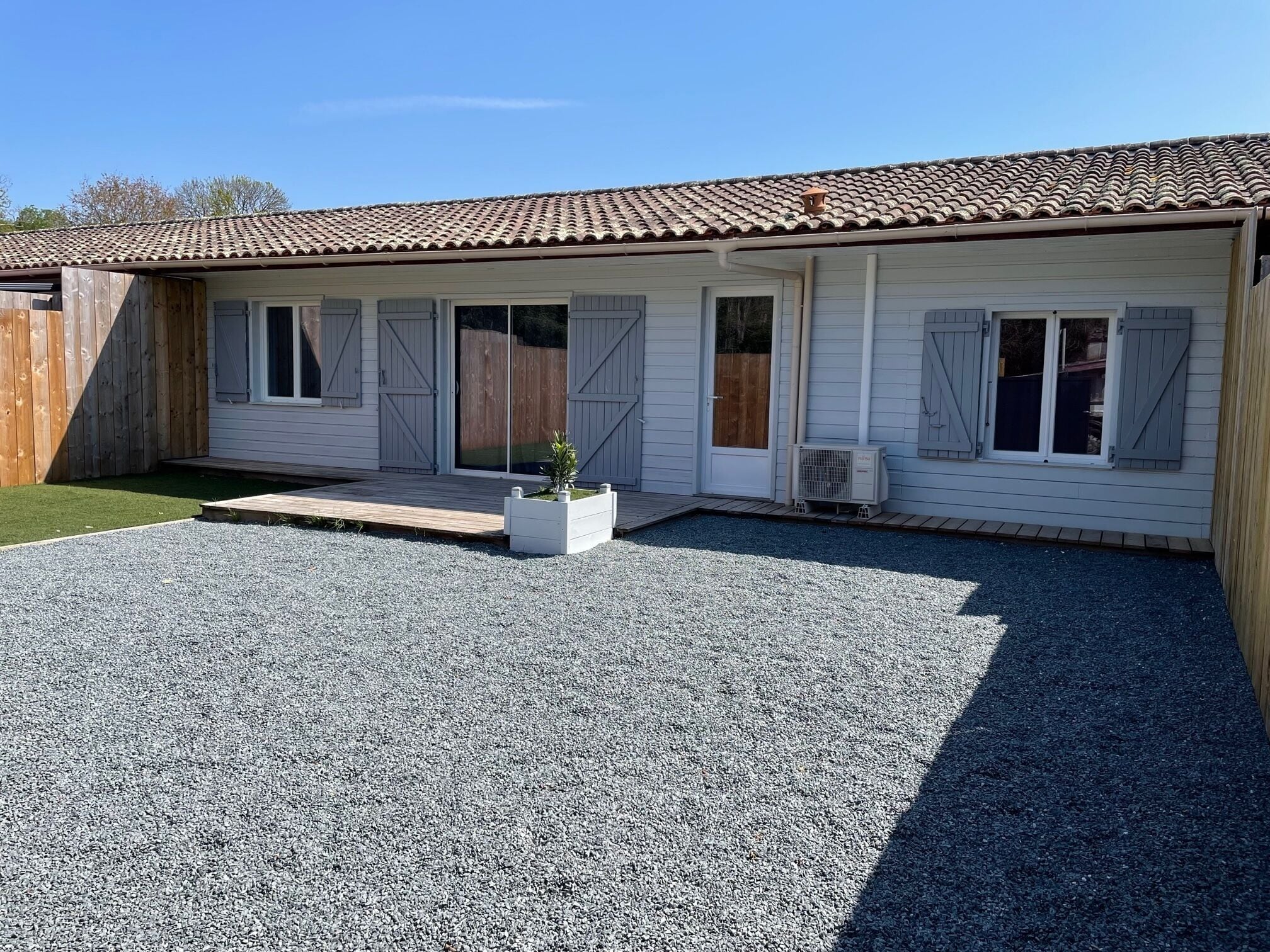 Una casa a due piani con tetto in tegole, un portico coperto e un vialetto sterrato.