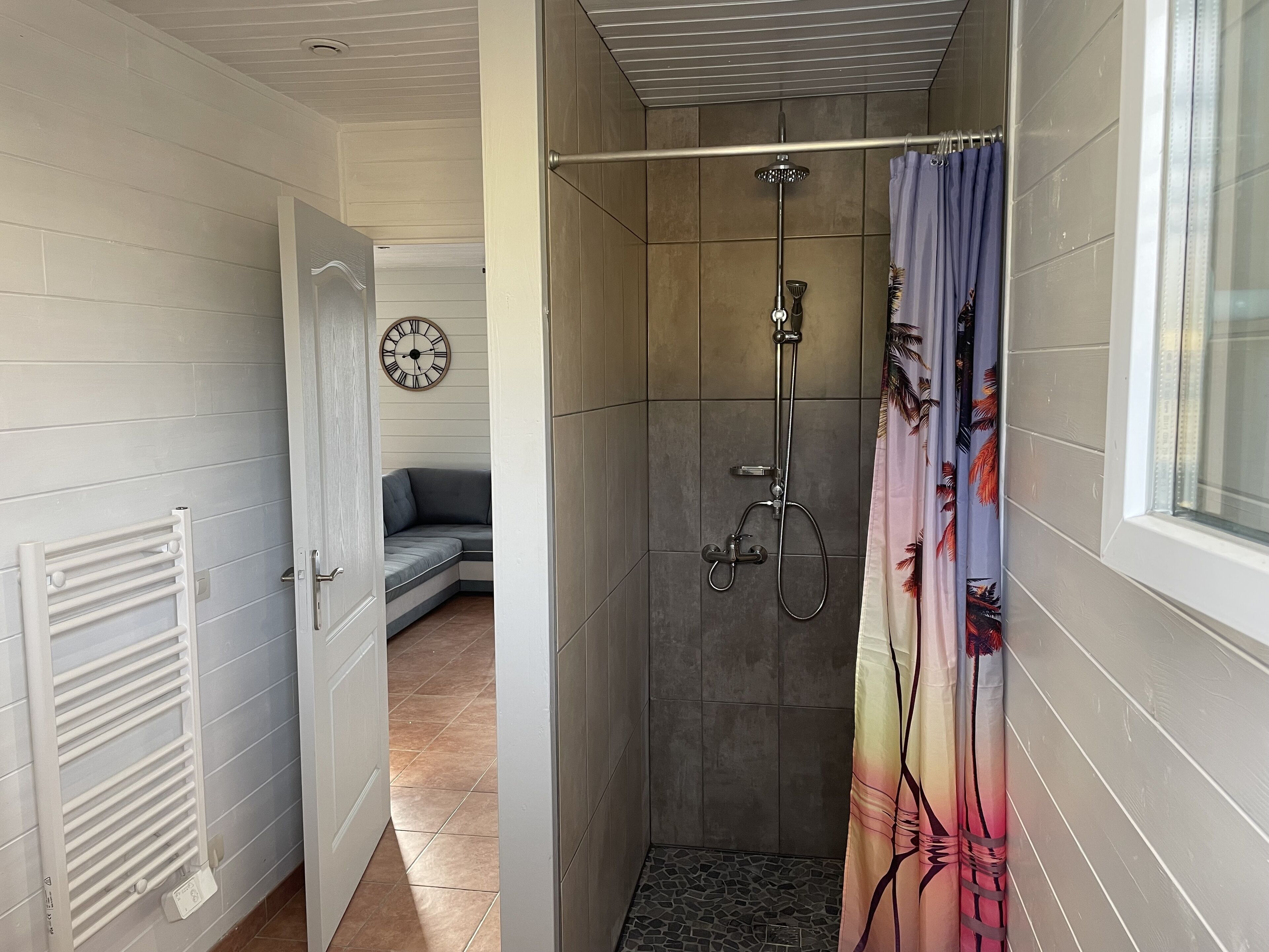 Une douche équipée d’un pommeau de douche à main et d’un rideau.