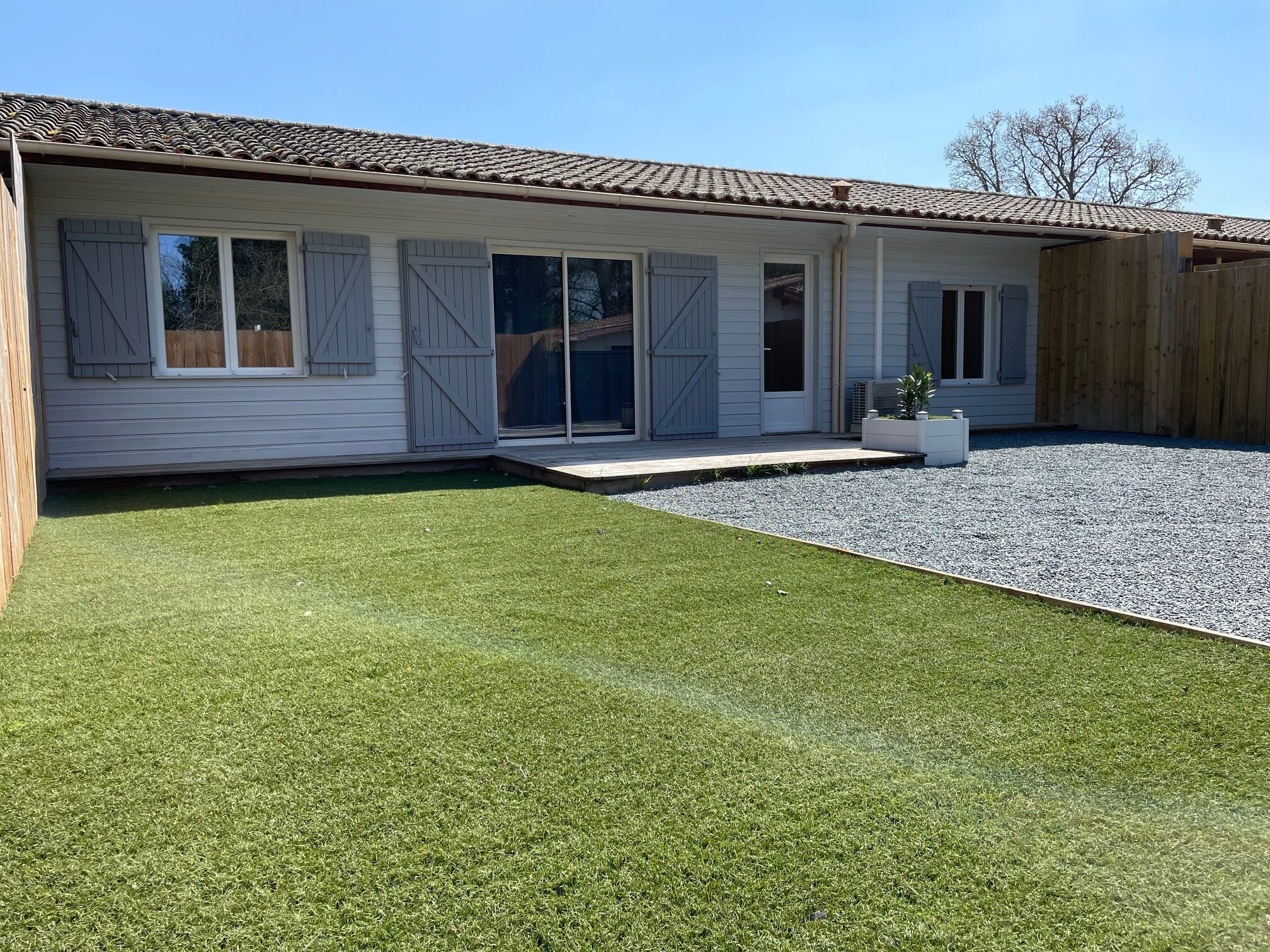 Une maison dotée d’un patio couvert, d’une cour clôturée et d’une allée en gravier.