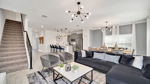 A modern living room with a black sectional sofa, a coffee table, and a staircase. - BBQ, Splash Pool & FREE Resort Access! Near WDW. (Kissimmee)