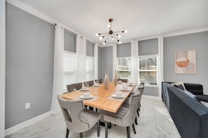 Gather around the banquet-style dining table, which comfortably seats 8 people. This inviting space is perfect for enjoying delicious meals, engaging in lively conversations, and creating lasting memories with family and friends. - Luxe 5BR Townhouse w/ Pool & Mickey-Themed Room (Kissimmee)