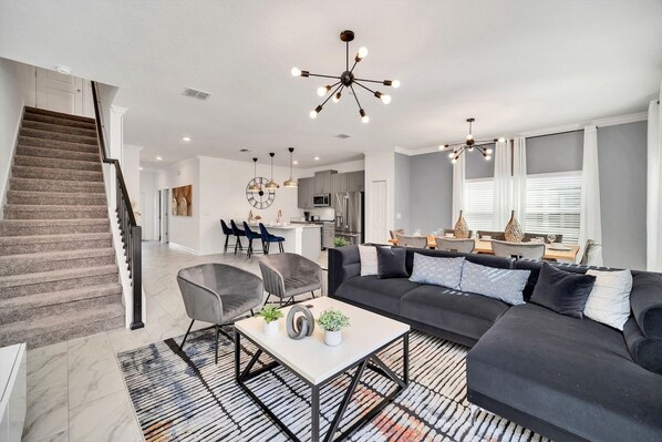 A modern living room with a black sectional sofa, a coffee table, and a staircase leading to another level.