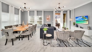 A modern dining area with a wooden table, grey upholstered chairs, and a black sofa. - BBQ, Splash Pool & FREE Resort Access! Near WDW. (Kissimmee)