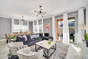 A modern living room with a sectional sofa, a coffee table, and a chandelier. - Luxe 5BR Townhouse w/ Pool & Mickey-Themed Room (Kissimmee)