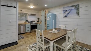 Una cocina compacta con electrodomésticos modernos, una mesa de comedor con sillas y un cuadro decorativo en la pared.