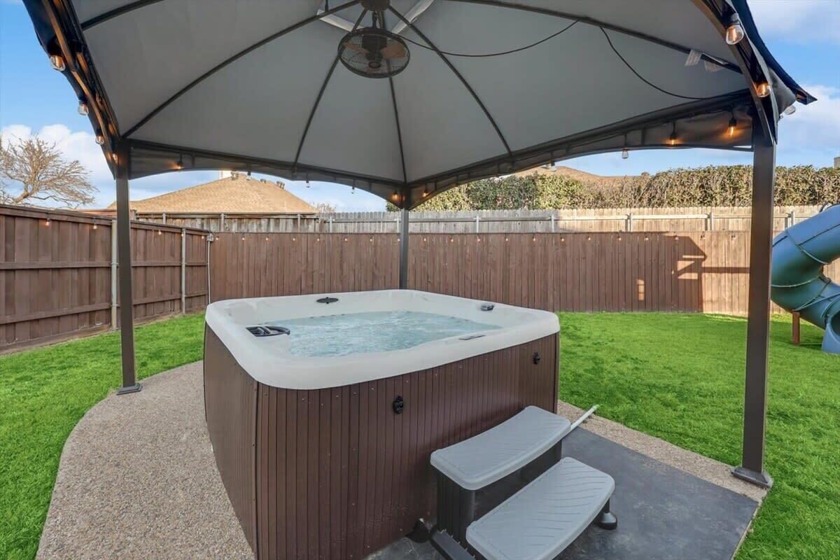 A hot tub under a covered patio with steps leading up to it.