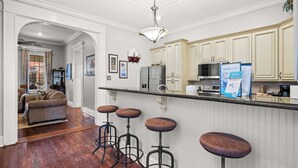 A modern kitchen with white cabinetry, a bar area with stools, and a dining area with a sofa. - Game Room, Back Yard, Close to Stadiums & Downtown (Covington)