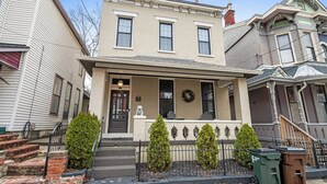 A two-story house with a front porch, a small statue, and two Christmas wreaths. - Game Room, Back Yard, Close to Stadiums & Downtown (Covington)