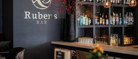 Un bar llamado 'Rubens BAR' con una variedad de botellas de licor y vasos en estanterías.