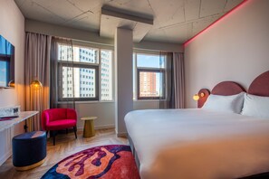 Una habitación de hotel con una cama grande, un escritorio, una silla y una mesita redonda.
