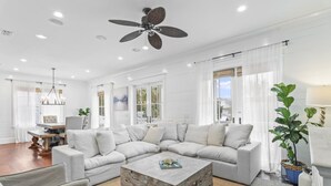 A spacious living room with a large sectional sofa, a wooden coffee table, and a ceiling fan.