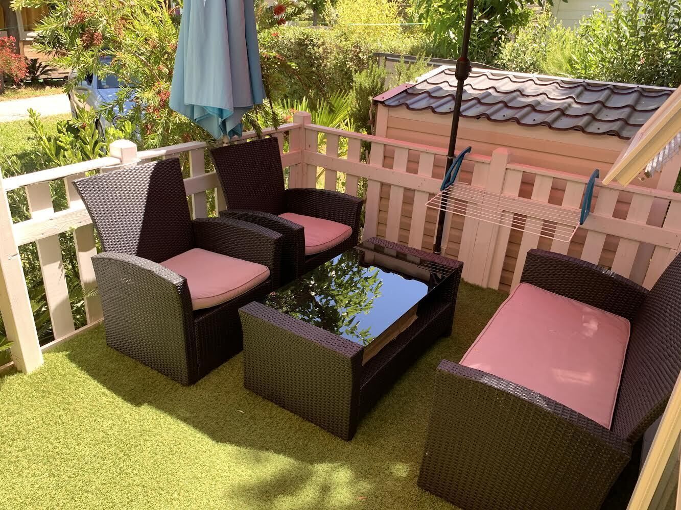 A patio with wicker furniture, a small water feature, and a playhouse in the background.