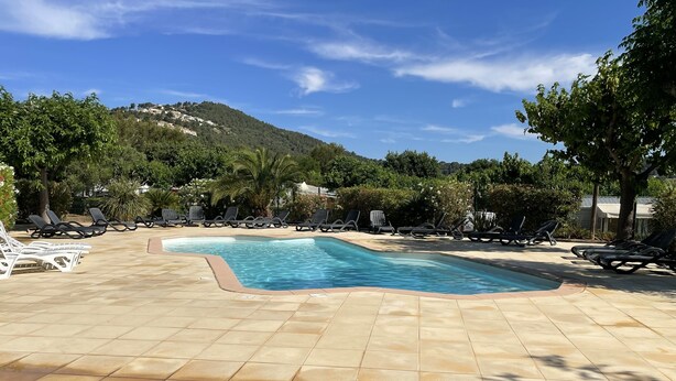 Una piscina amb gandules i un paisatge amb muntanyes al fons.