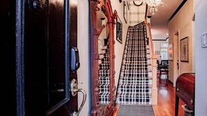 A staircase with a checkered carpet leading to a landing area with a wooden bench and a mailbox. - Heart of Capitol Hill Row House, Luxury & Location (Washington)