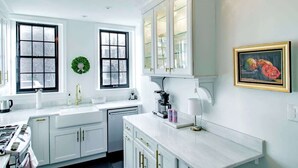 A modern kitchen with white cabinets, a large window, and a coffee maker. - Heart of Capitol Hill Row House, Luxury & Location (Washington)