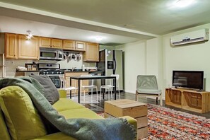 A compact living space with a kitchenette, a sofa, a TV, and a patterned rug.