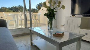Moderni huone, jossa on lasipöytä, valkoinen kaappi ja televisio.