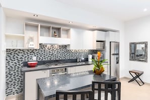Et moderne køkken med en backsplash i sort og hvid fliser, rustfrie stålemmer og en central ø med siddepladser.