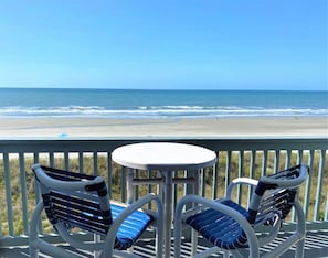 A balcony with two chairs and a table, overlooking a beach with the ocean in the background. - Beach Master 305 Summ (North Myrtle Beach)