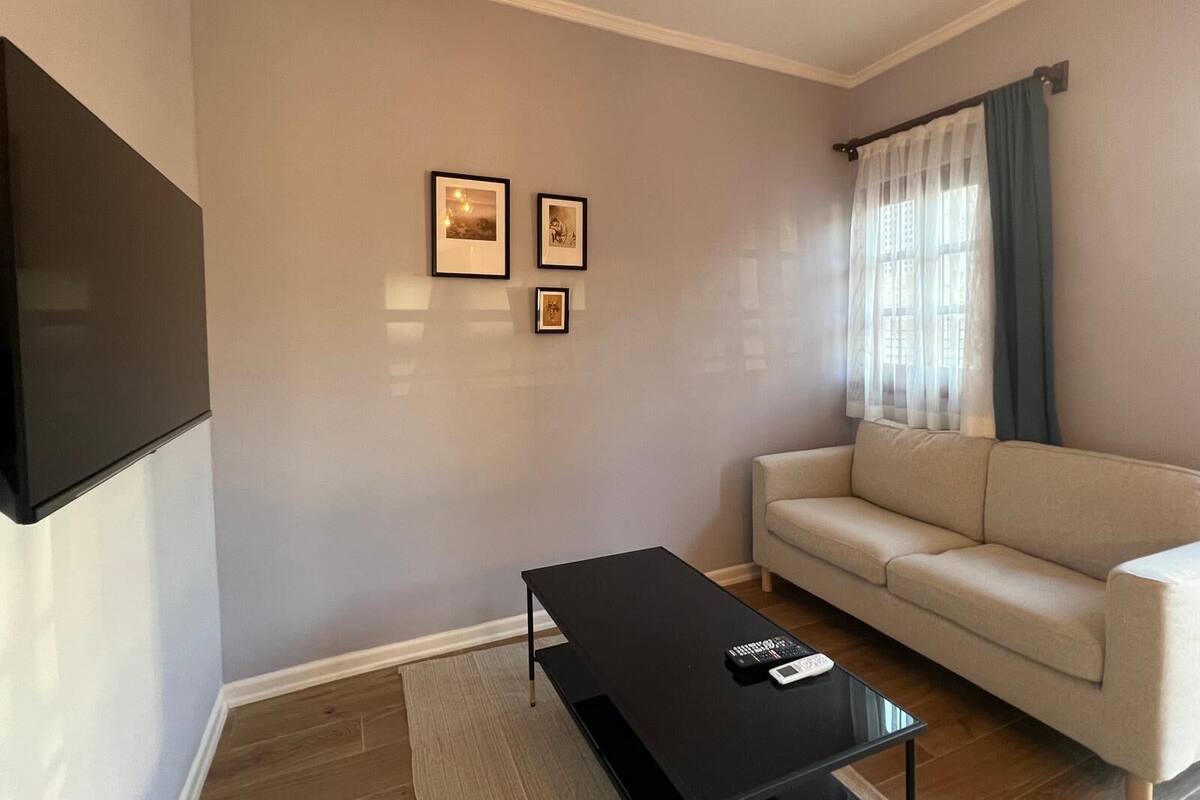 Un salon comprenant un canapé, une table basse et un téléviseur à écran plat fixé au mur.