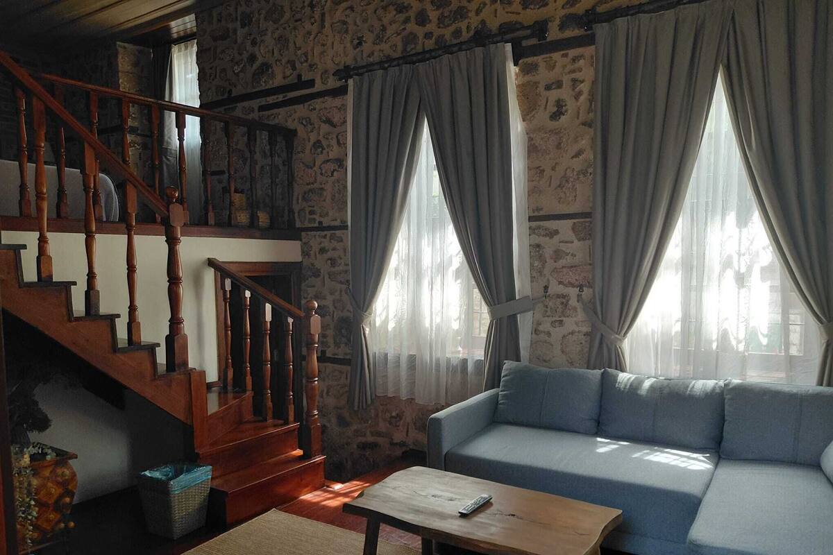Un salon avec un escalier en bois, un canapé bleu et une table basse en bois.